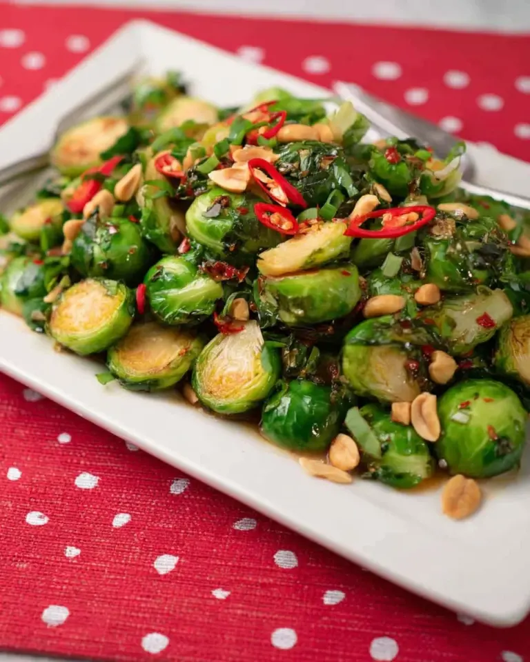 Brussel sprouts drizzled with flavorful Thai dressing on a plate.