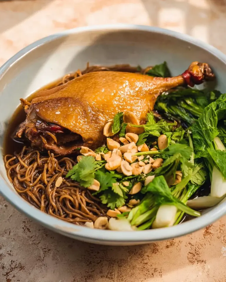 Bowl of Thai Duck Noodle Soup garnished with herbs and spices