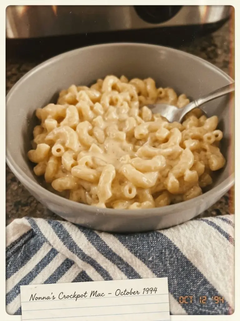 Creamy crockpot mac and cheese garnished with herbs in a serving dish.