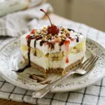 No-bake banana split cake topped with whipped cream and cherries